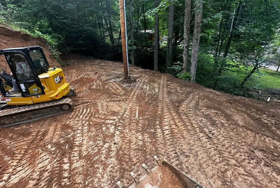 Excavator cutting a slope on a wooded lot