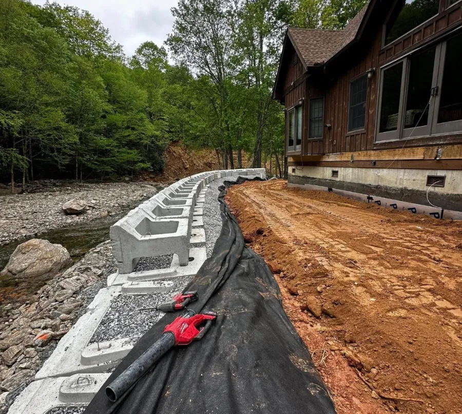 Retaining wall base with drainage fabric and pipe